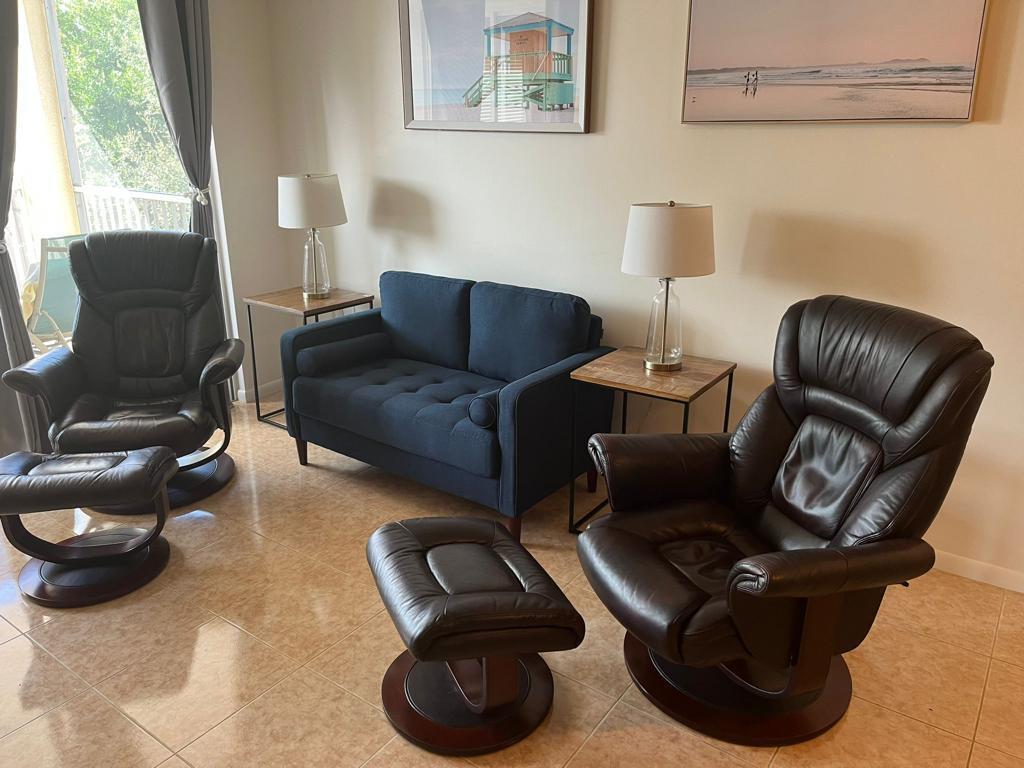 A living room features a blue loveseat flanked by two leather recliners with matching ottomans — 353 S Us Highway 1 # B309, Jupiter FL 33477, JUPITER, FL