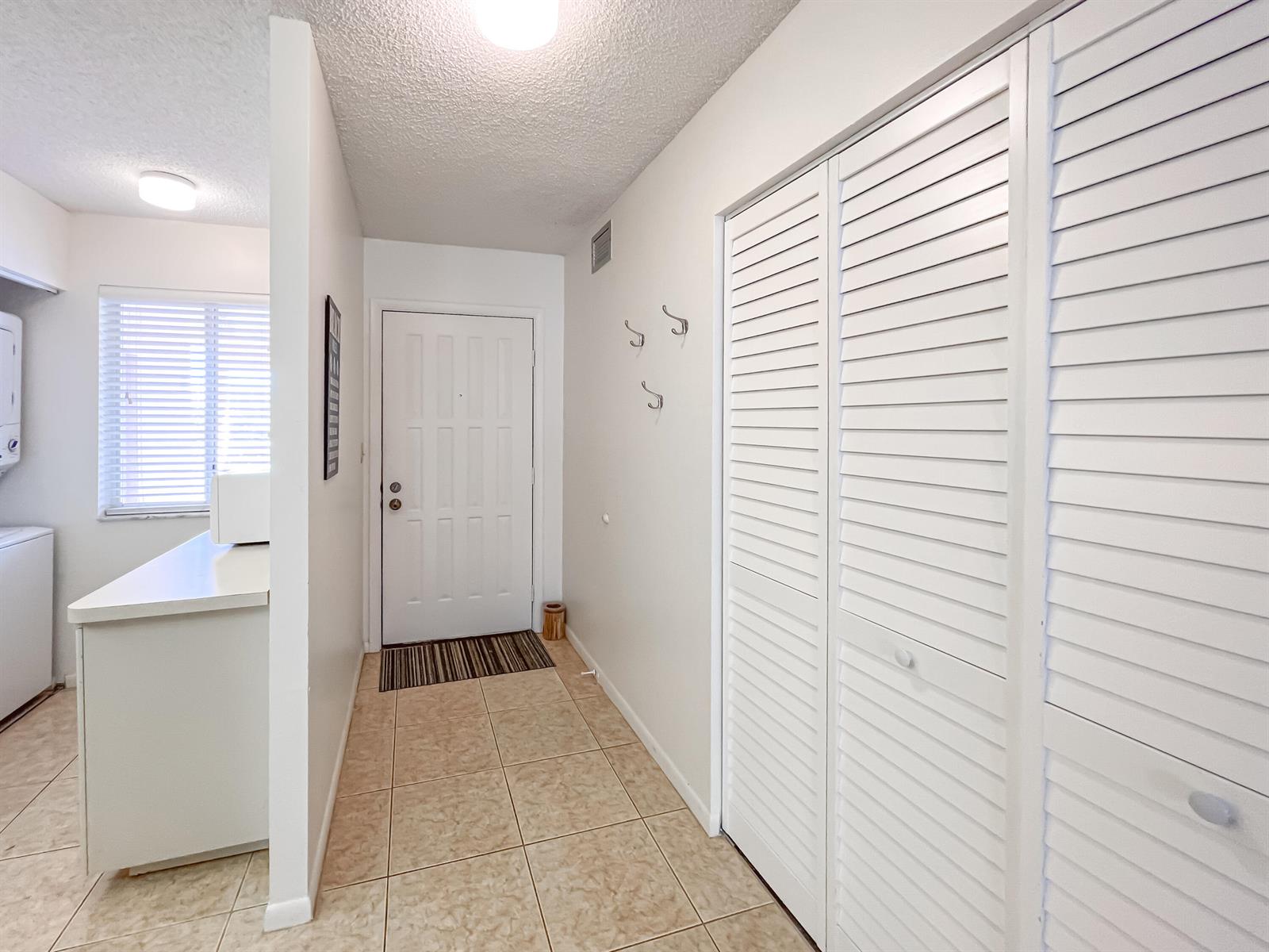 A tiled entryway features a white front door, wall hooks, and a louvered closet door — 353 S Us Highway 1 # B309, Jupiter FL 33477, JUPITER, FL