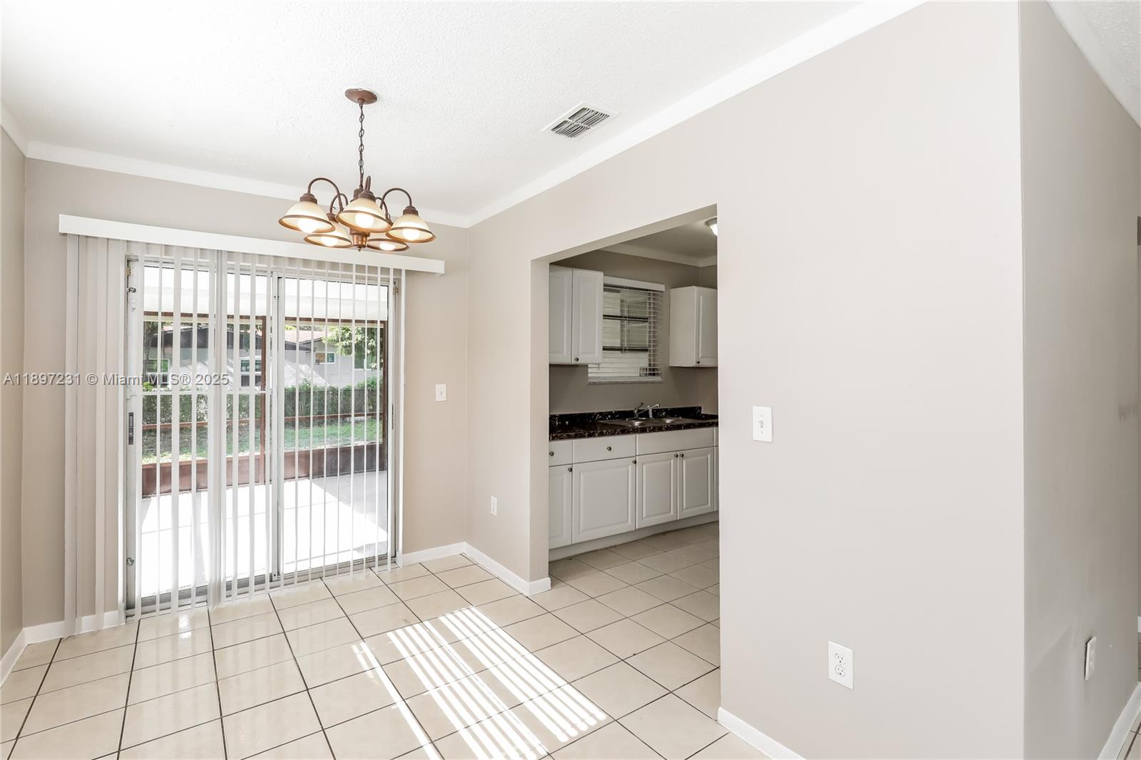 A dining area with tile floors and a sliding glass door leads to a kitchen — 381 NE 164th St # 0, Miami FL 33162, MIAMI, FL