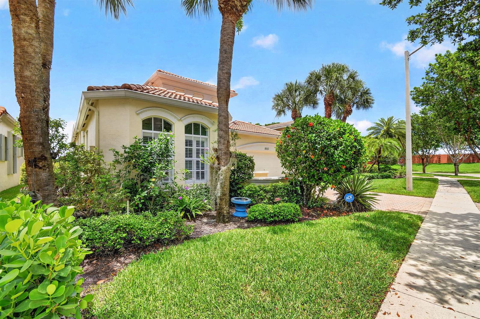 A single-story house with a tile roof, arched windows, and palm trees in the front yard — 8553 E Via Grande E, Wellington FL 33411, WELLINGTON, FL