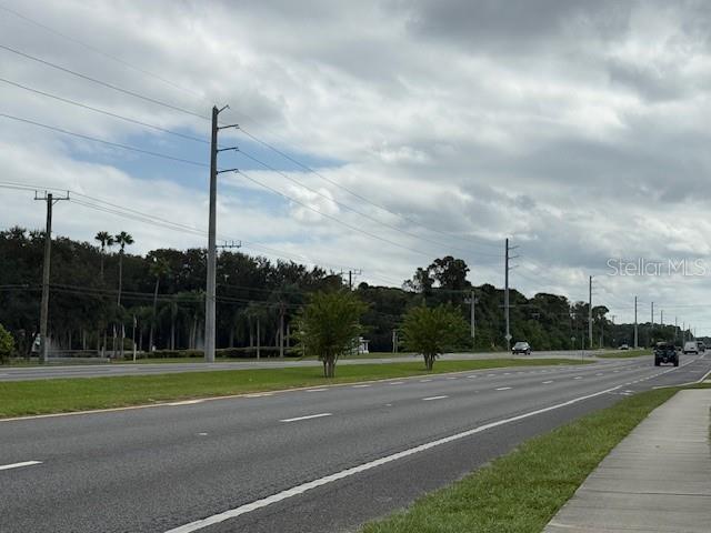 A multi-lane road stretches past a grassy median and a line of trees under clouds — 2794 S RIDGEWOOD AVENUE S, EDGEWATER, FL