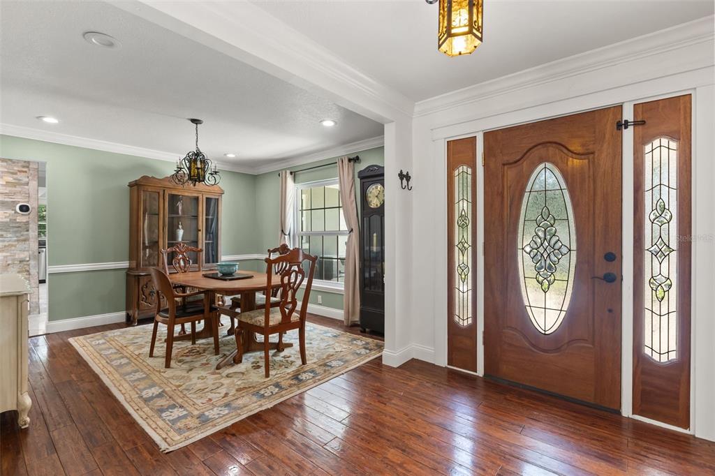 A dining room with a wooden table and hutch sits beside a wooden front door — 2080 GOLDWATER COURT, MAITLAND, FL