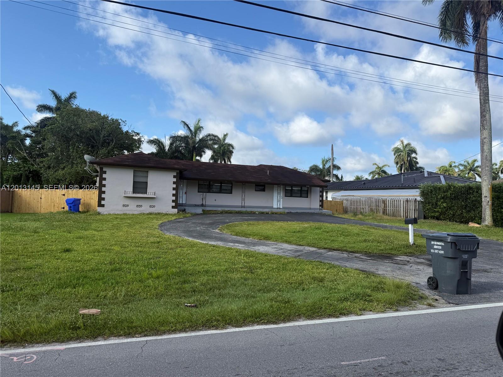 A single-story house with a curved driveway and palm trees sits on a grassy lot — 2830 Johnson St # 1, Hollywood FL 33020, HOLLYWOOD, FL
