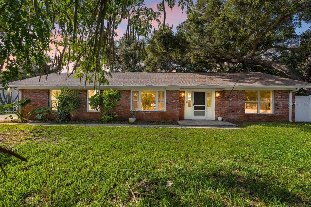 A single-story brick house with a shingled roof sits behind a large grassy lawn — 13589 101ST TERRACE, SEMINOLE, FL