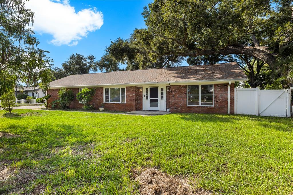 A single-story brick house with a shingled roof sits behind a large green lawn — 13589 101ST TERRACE, SEMINOLE, FL