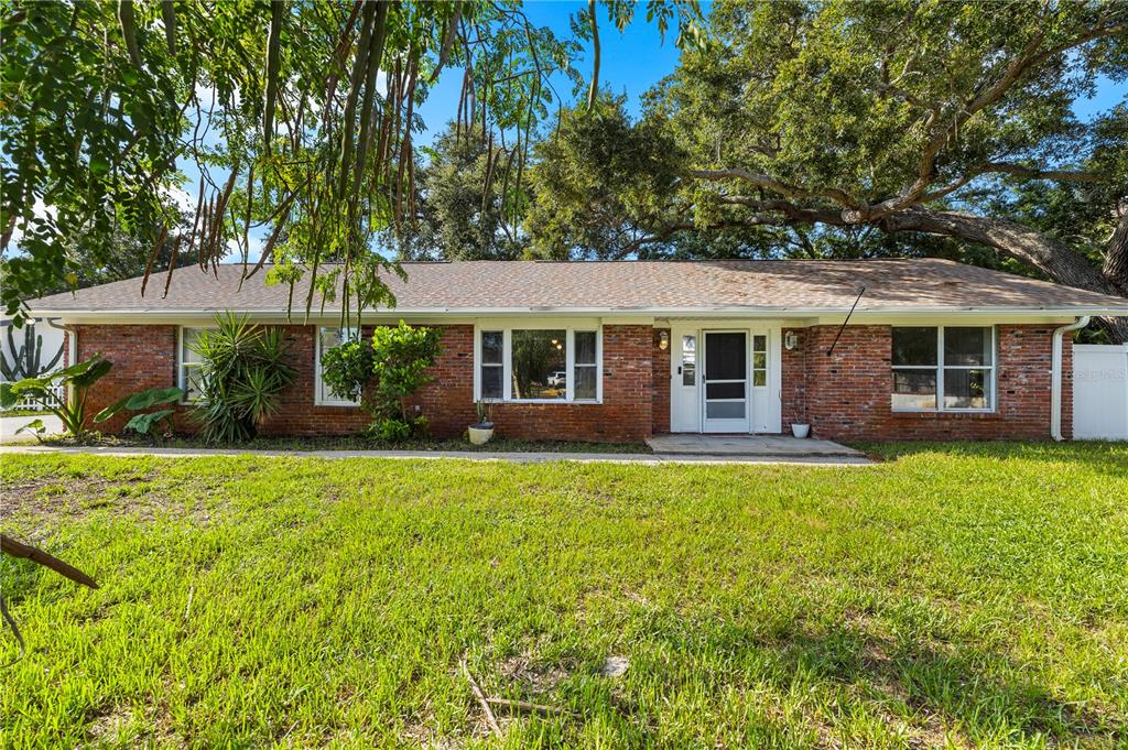 A single-story brick house with a shingled roof sits behind a large grassy lawn — 13589 101ST TERRACE, SEMINOLE, FL