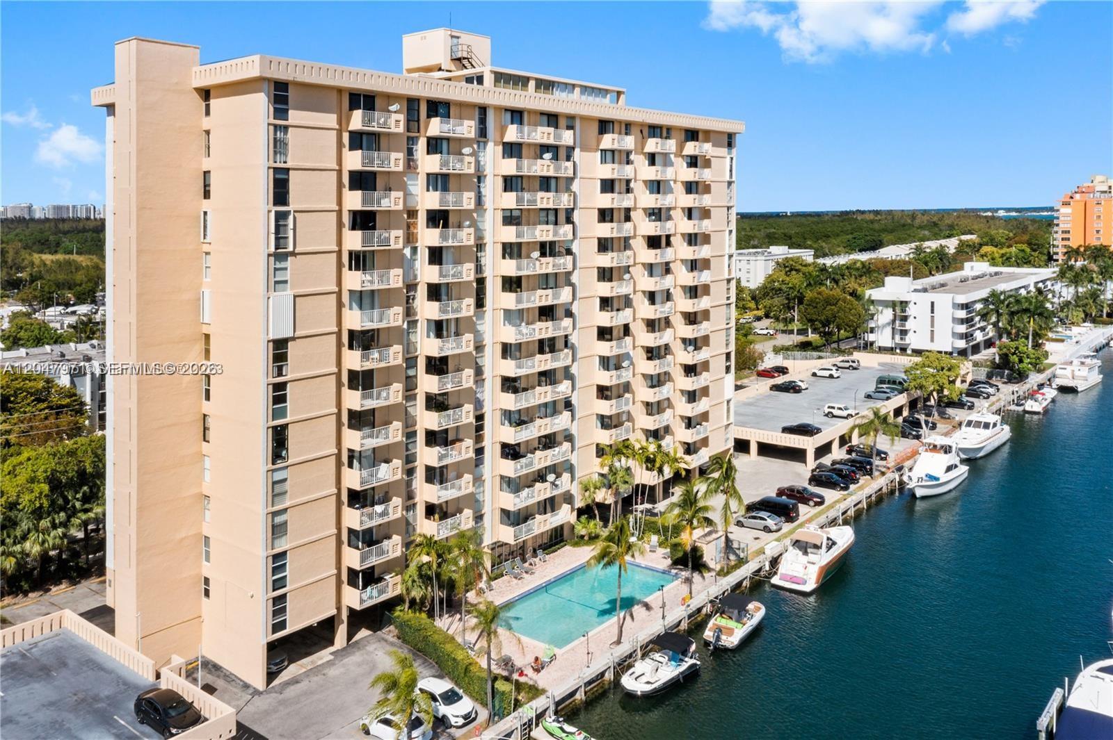 An aerial view shows a tan high-rise apartment building with a pool and boat slips — 2350 NE 135th St # 403, North Miami FL 33181, NORTH MIAMI, FL