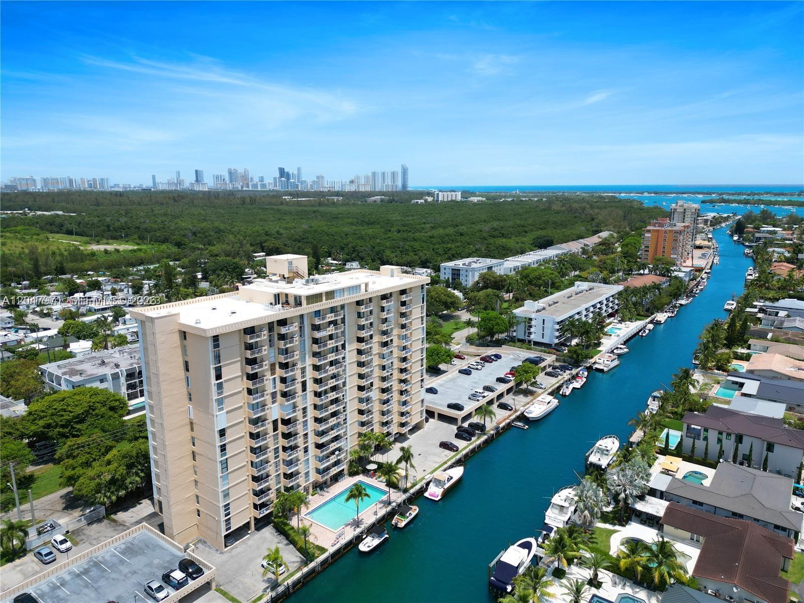 An aerial view shows a tall apartment building with a pool beside a canal — 2350 NE 135th St # 403, North Miami FL 33181, NORTH MIAMI, FL