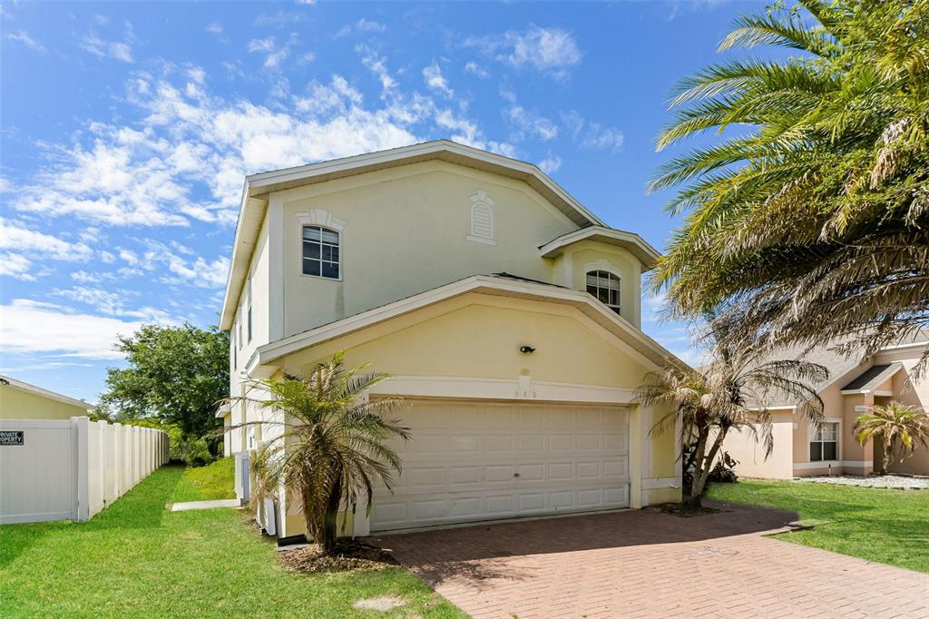 A two-story house with a pale yellow exterior, a two-car garage, and a palm tree — 948 CHANLER DRIVE, HAINES CITY, FL