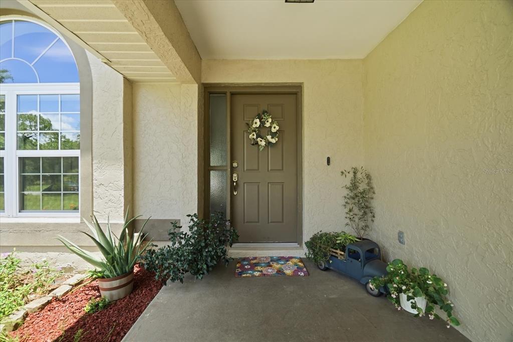 A front entryway features a brown door with a side light and potted plants — 2877 W AXELWOOD DRIVE, BEVERLY HILLS, FL