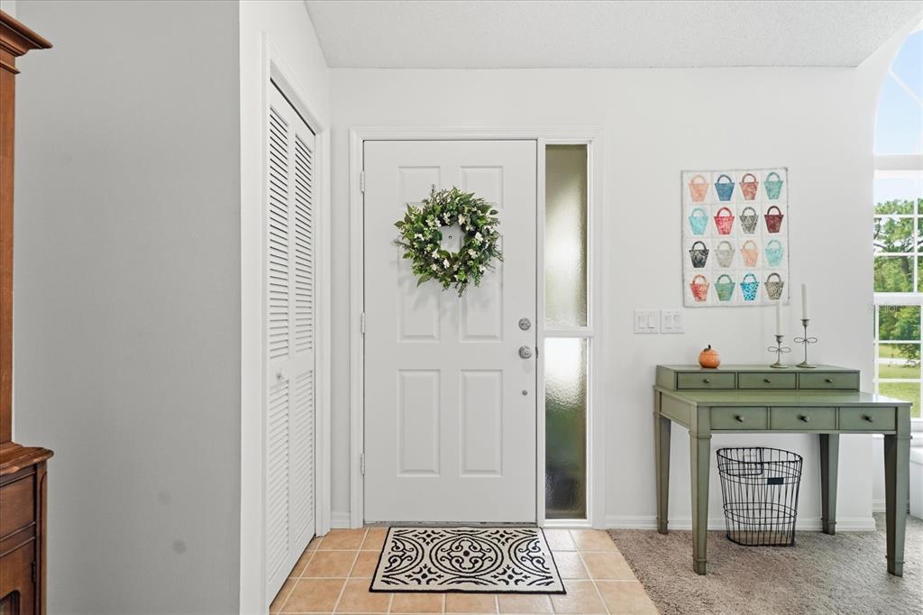 An entryway features a white front door, a side window, a green console table, and tile — 2877 W AXELWOOD DRIVE, BEVERLY HILLS, FL