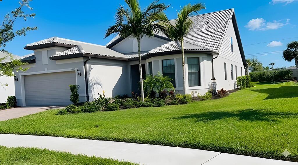 A single-story house with a gray roof, light-colored stucco walls, and two palm trees — 12457 GOLDEN SAGE DRIVE, SARASOTA, FL