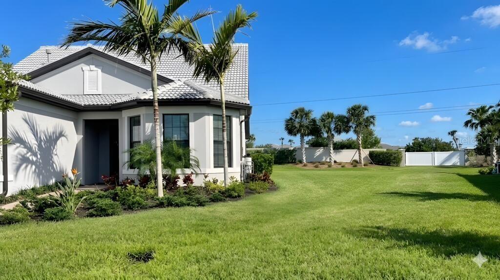 A side view of a light-colored house with a tiled roof and palm trees — 12457 GOLDEN SAGE DRIVE, SARASOTA, FL
