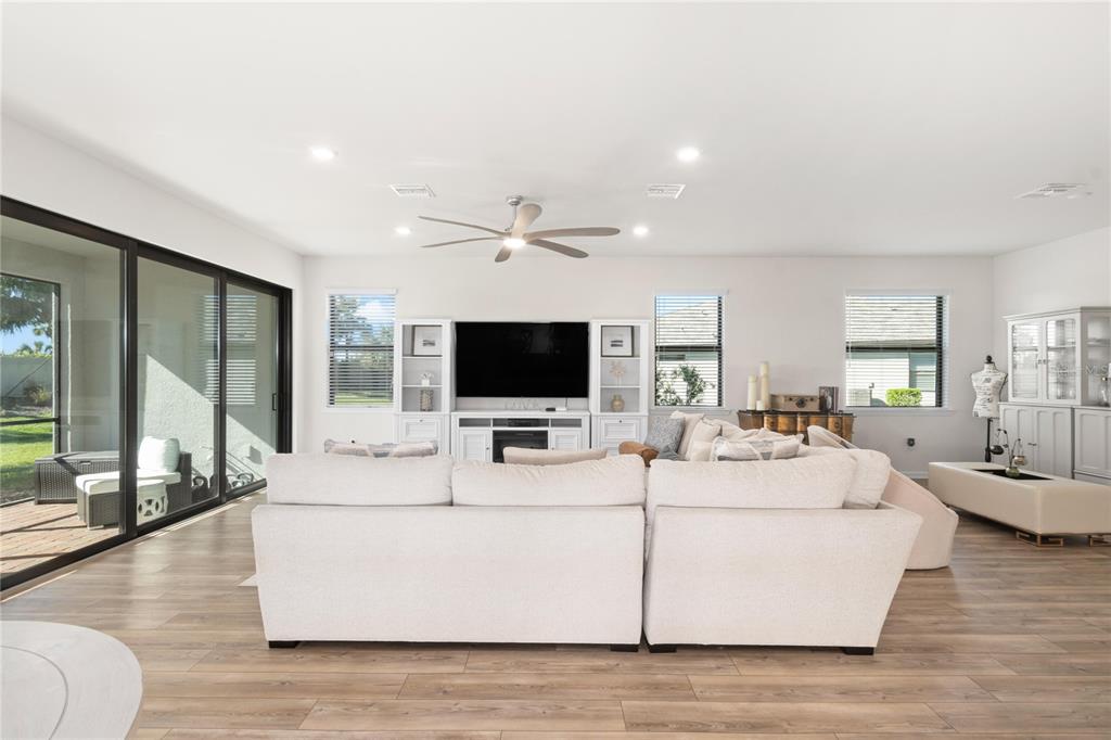A living room features a large sectional sofa, a television console, and sliding glass doors — 12457 GOLDEN SAGE DRIVE, SARASOTA, FL