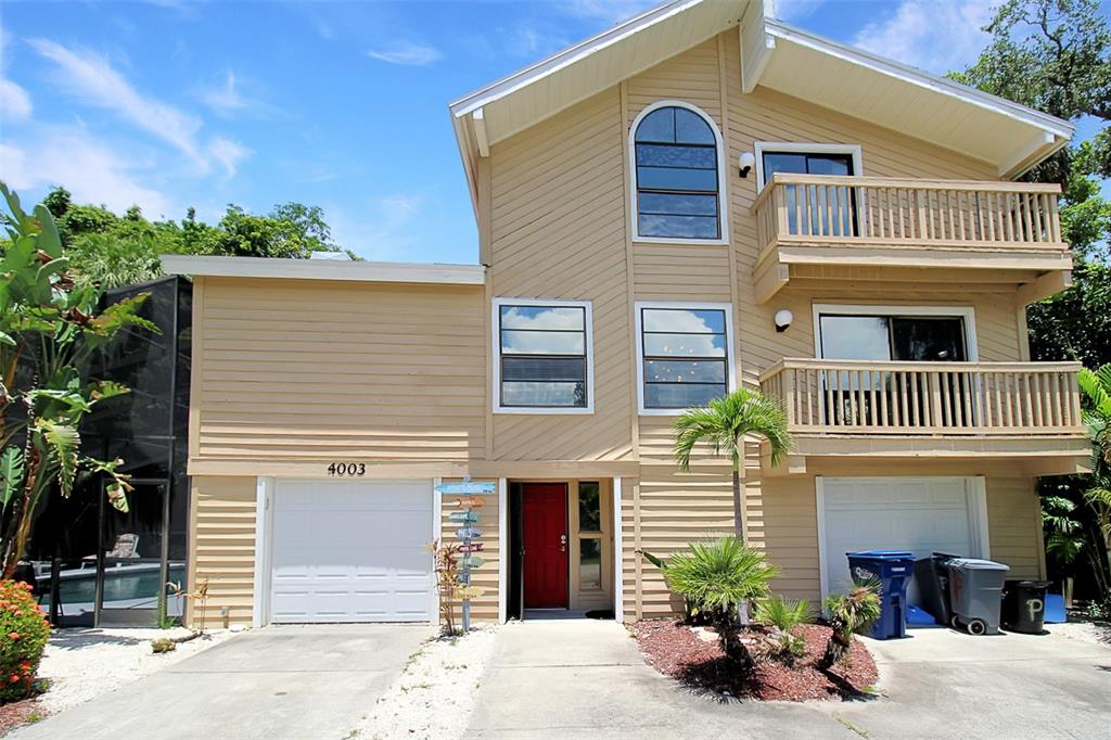 A three-story tan house with two garages, two balconies, and a red front door — 4003 BAYSIDE COURT, BRADENTON, FL