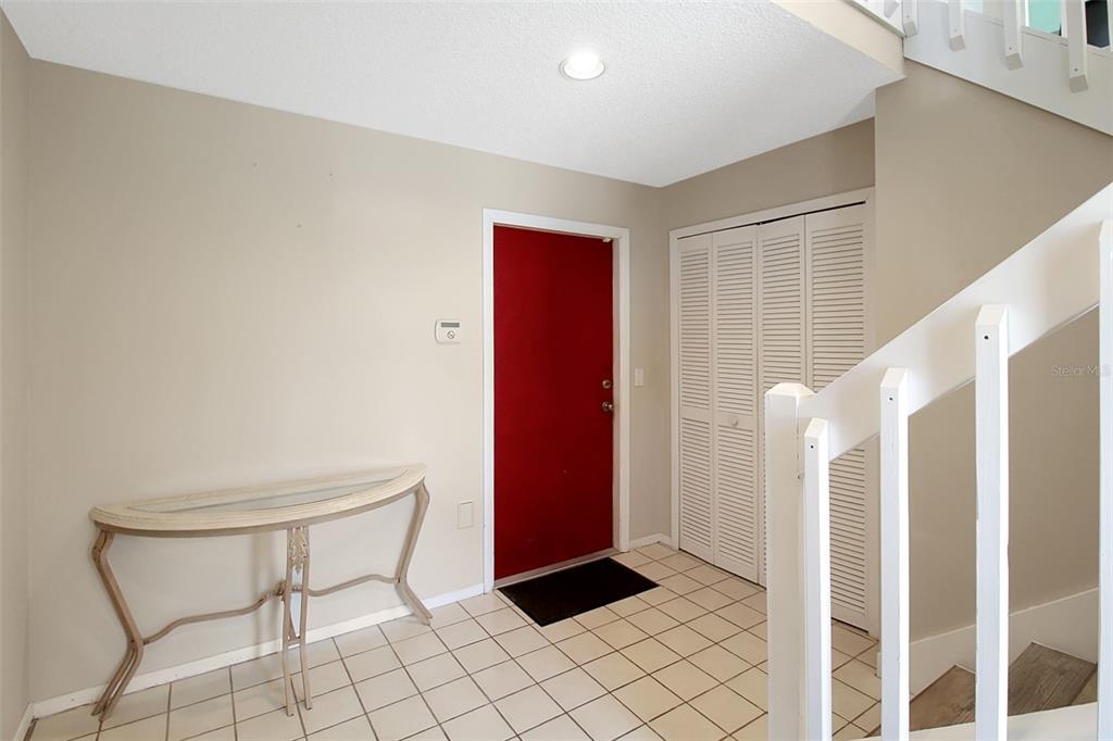 An entryway features a red front door, tiled floor, white staircase railing, and a console table — 4003 BAYSIDE COURT, BRADENTON, FL