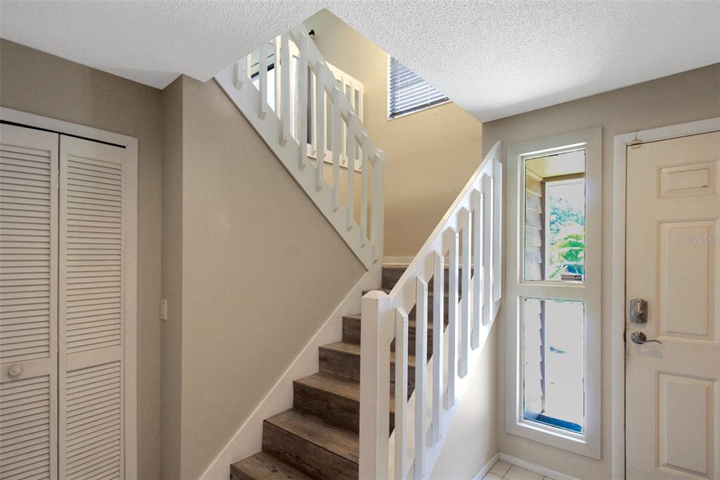 An interior entryway features a staircase with wood-look treads, white railings, and a front door — 4003 BAYSIDE COURT, BRADENTON, FL