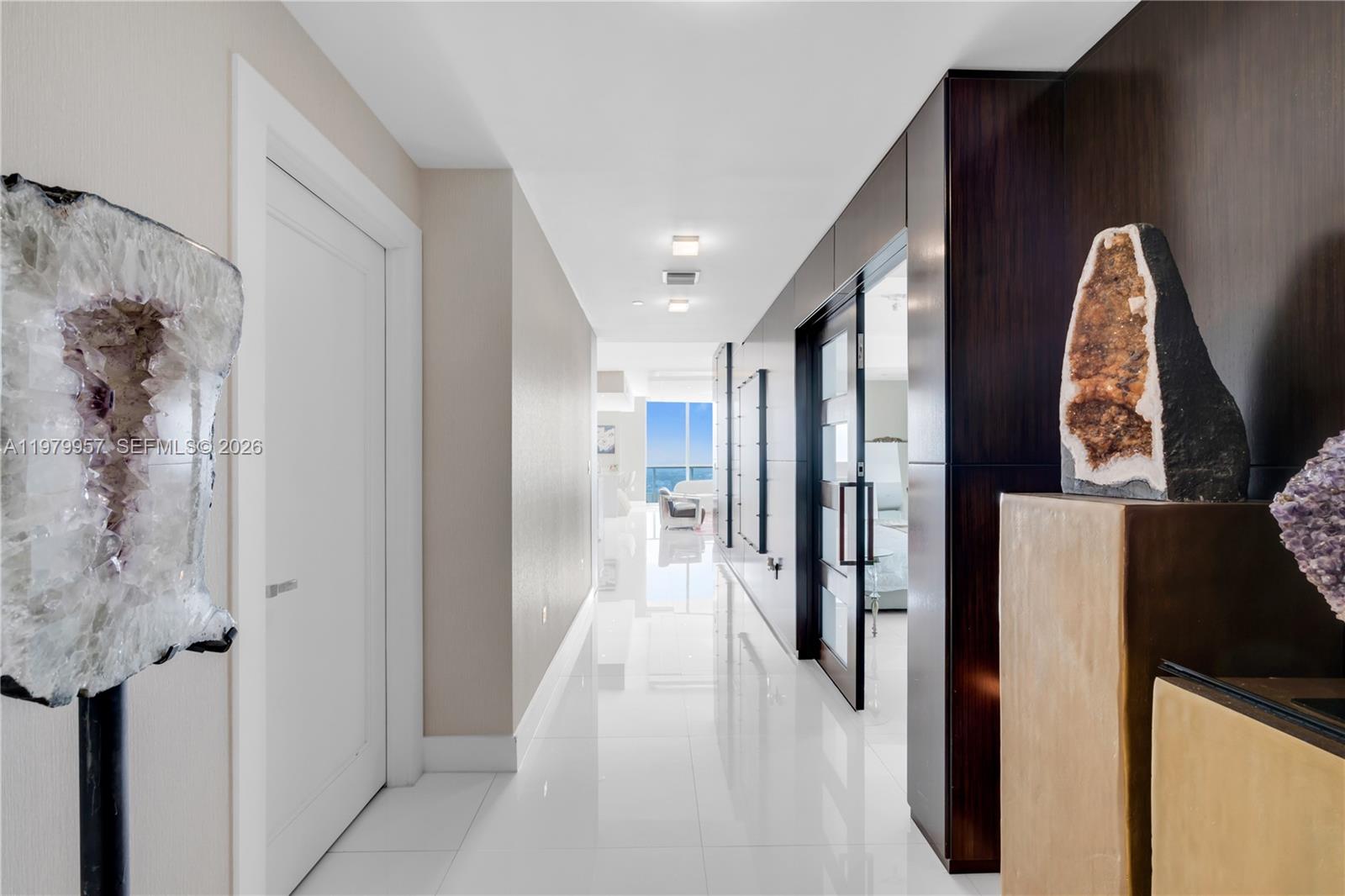 A bright hallway features white tile floors, dark wood paneling, and large crystal decor pieces — 900 Biscayne Blvd, Miami FL 33132, MIAMI, FL