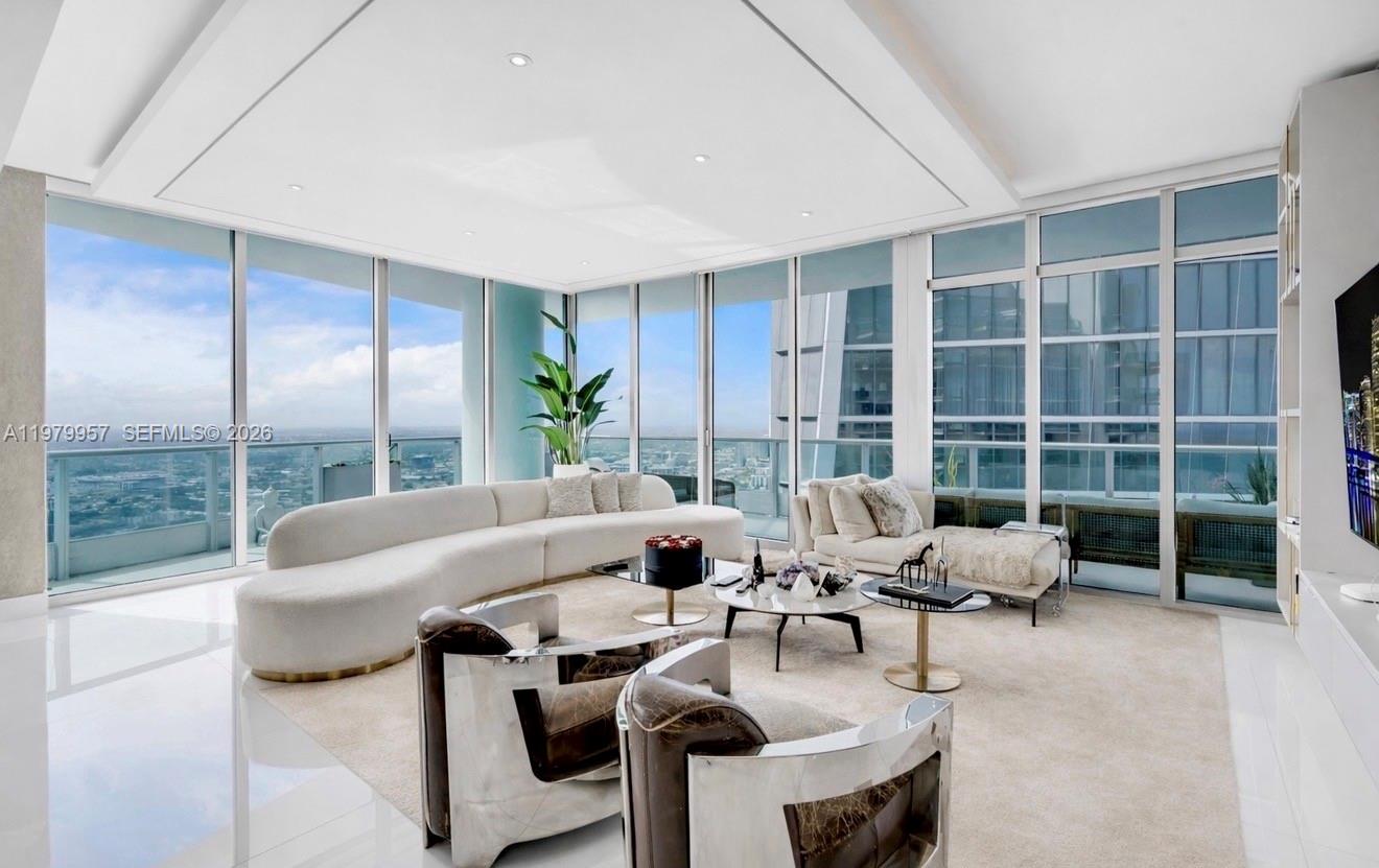 A modern living room features floor-to-ceiling windows, a curved sofa, and marble-patterned armchairs — 900 Biscayne Blvd, Miami FL 33132, MIAMI, FL
