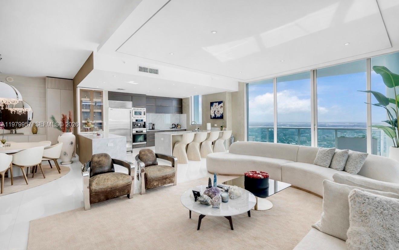 A modern open-concept living room and kitchen featuring floor-to-ceiling windows with expansive city views — 900 Biscayne Blvd, Miami FL 33132, MIAMI, FL