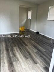 An empty room features gray wood-look flooring and light-colored walls with two windows — 1820 NW 127th St # 1820, Miami FL 33167, MIAMI, FL