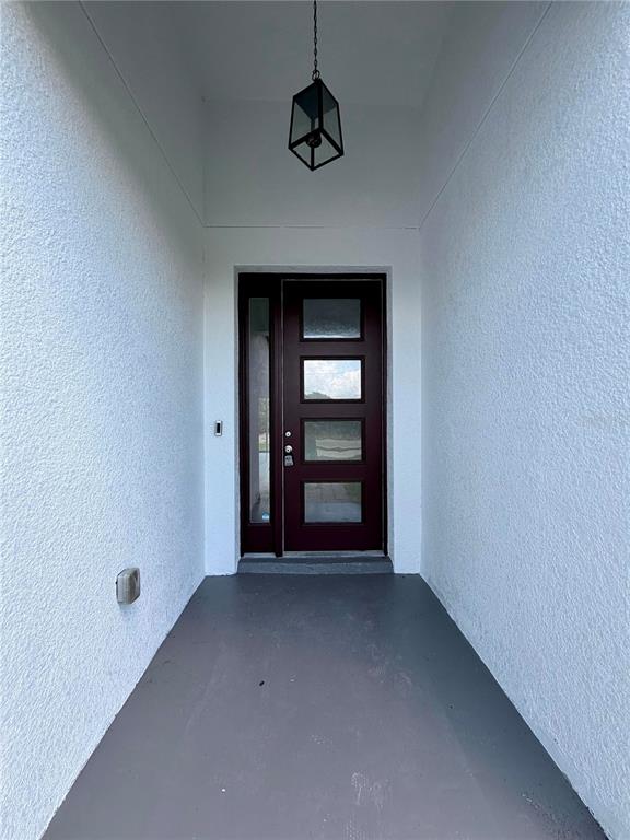 A covered entryway features a dark brown front door with glass panels and a hanging lantern — 14142 APPLETON BOULEVARD, PORT CHARLOTTE, FL