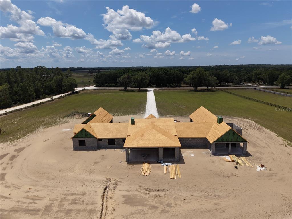 An aerial view shows a newly constructed gray farmhouse with a metal roof under construction — 14951 SE 60TH STREET, MORRISTON, FL