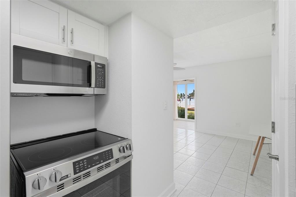 A kitchen with stainless steel appliances overlooks a tiled living area with a water view — 8921 BLIND PASS ROAD UNIT 144, ST PETE BEACH, FL