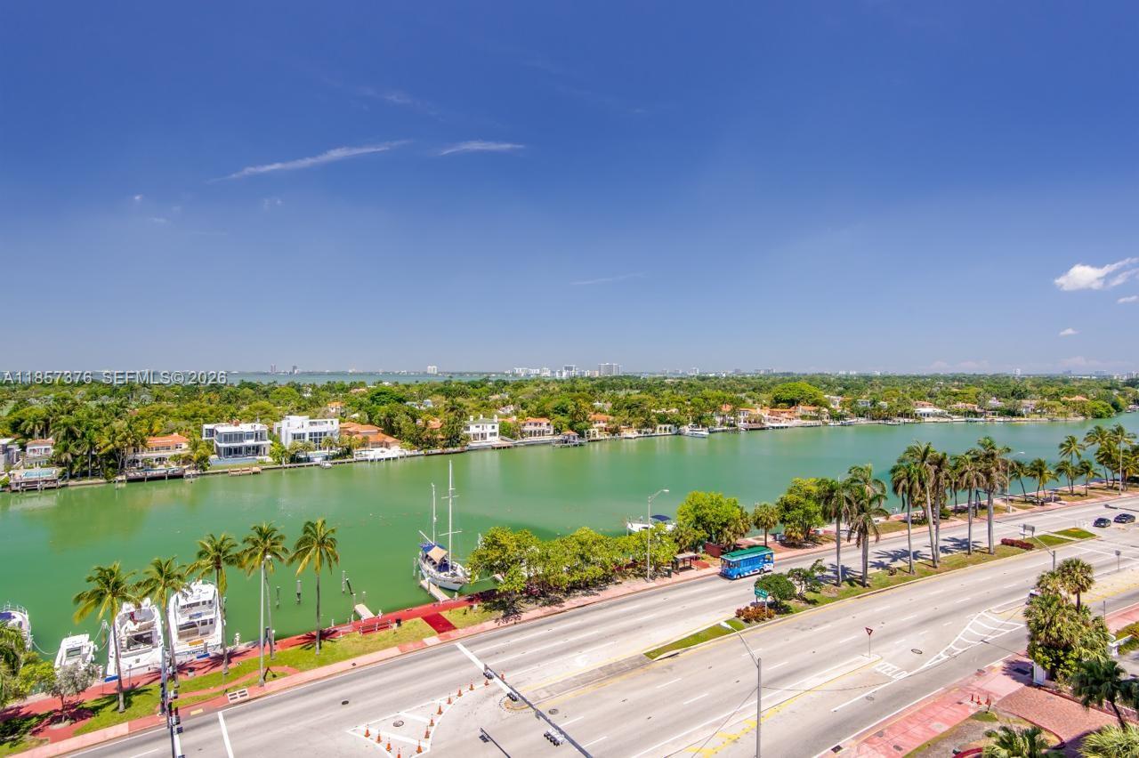 An elevated view of a waterway, palm trees, a road, and residential properties under a sky — 5161 Collins Ave # 1104, Miami Beach FL 33140, MIAMI BEACH, FL