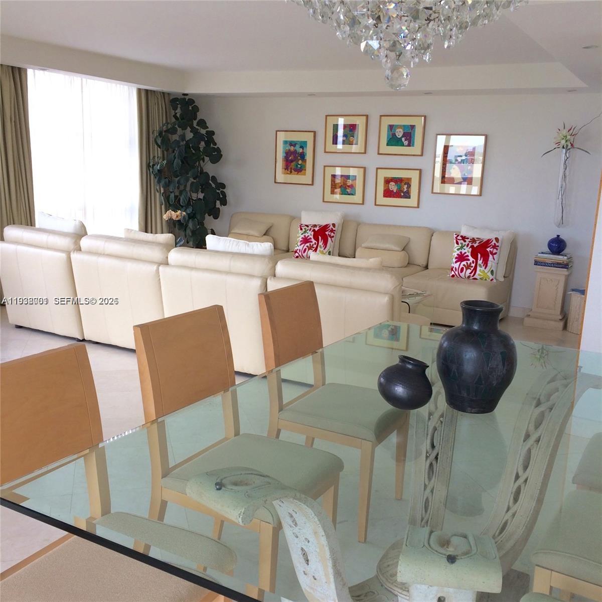 A dining area with a glass table overlooks a living room with a large sectional — 1121 Crandon Blvd # F1107, Key Biscayne FL 33149, KEY BISCAYNE, FL