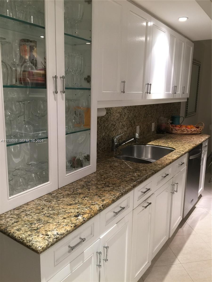 A kitchen features white cabinets, granite countertops, a stainless steel sink, and glass-front display cabinets — 1121 Crandon Blvd # F1107, Key Biscayne FL 33149, KEY BISCAYNE, FL