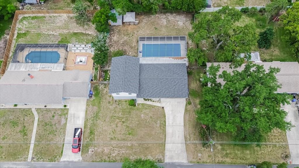 An aerial view shows three residential houses with swimming pools and driveways on a street — 115 W BRENTRIDGE DRIVE, BRANDON, FL
