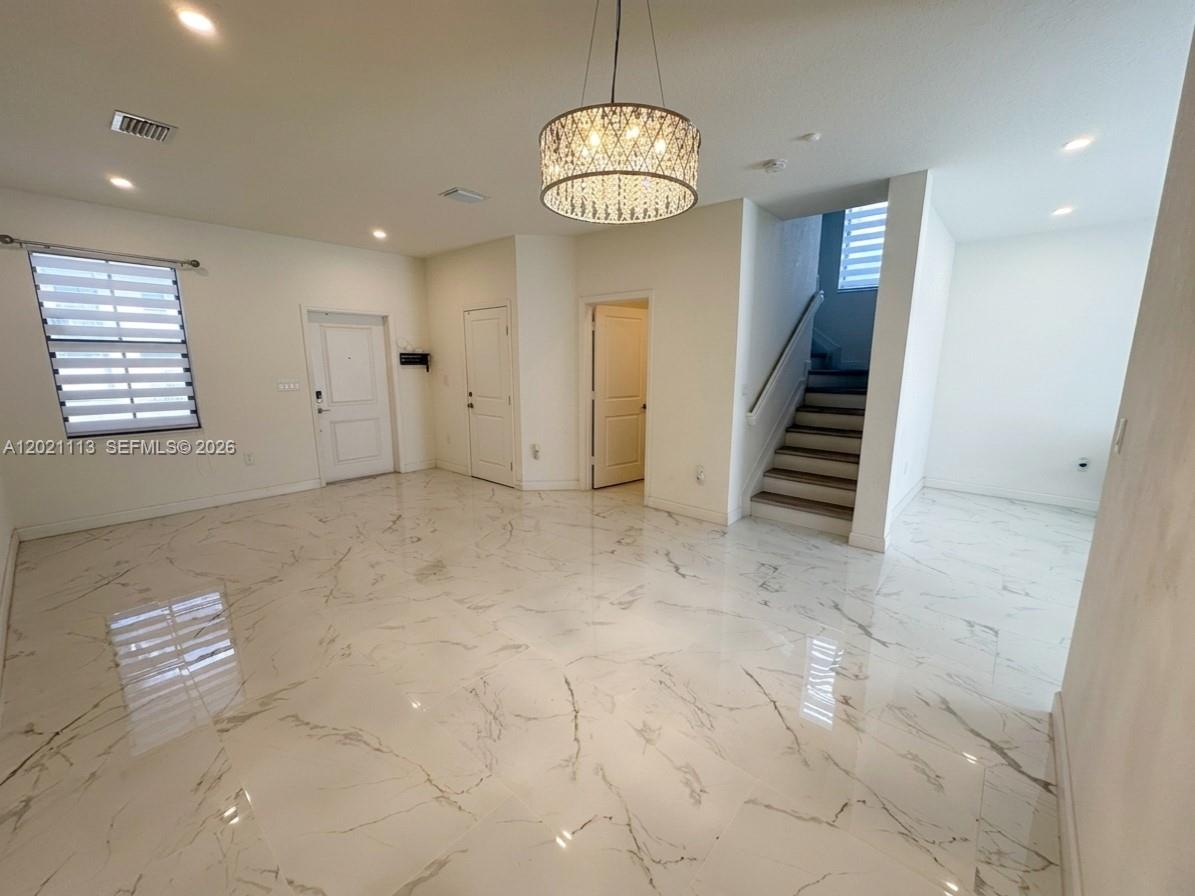 A bright, open-concept living area features white marble-look tile flooring and a decorative chandelier — 20352 NW 6th Ave, Miami Gardens FL 33169, MIAMI GARDENS, FL