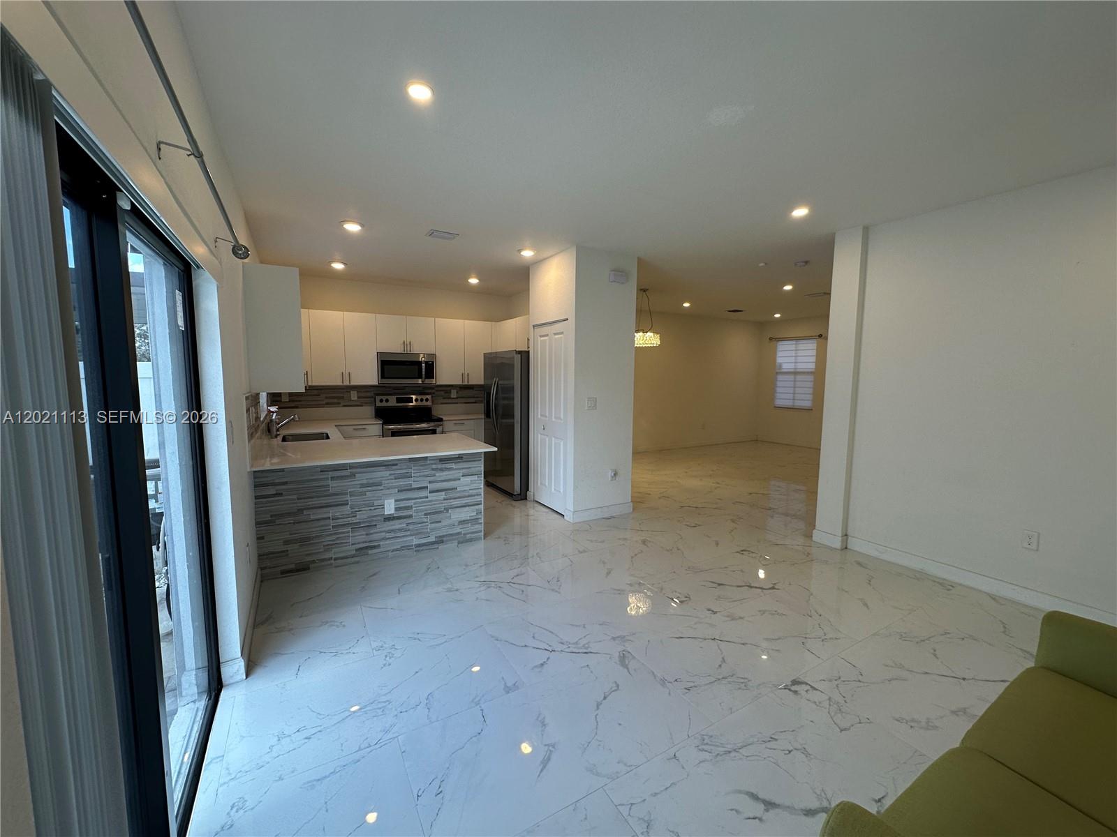 A kitchen with white cabinets and a tiled island opens into a spacious living area — 20352 NW 6th Ave, Miami Gardens FL 33169, MIAMI GARDENS, FL