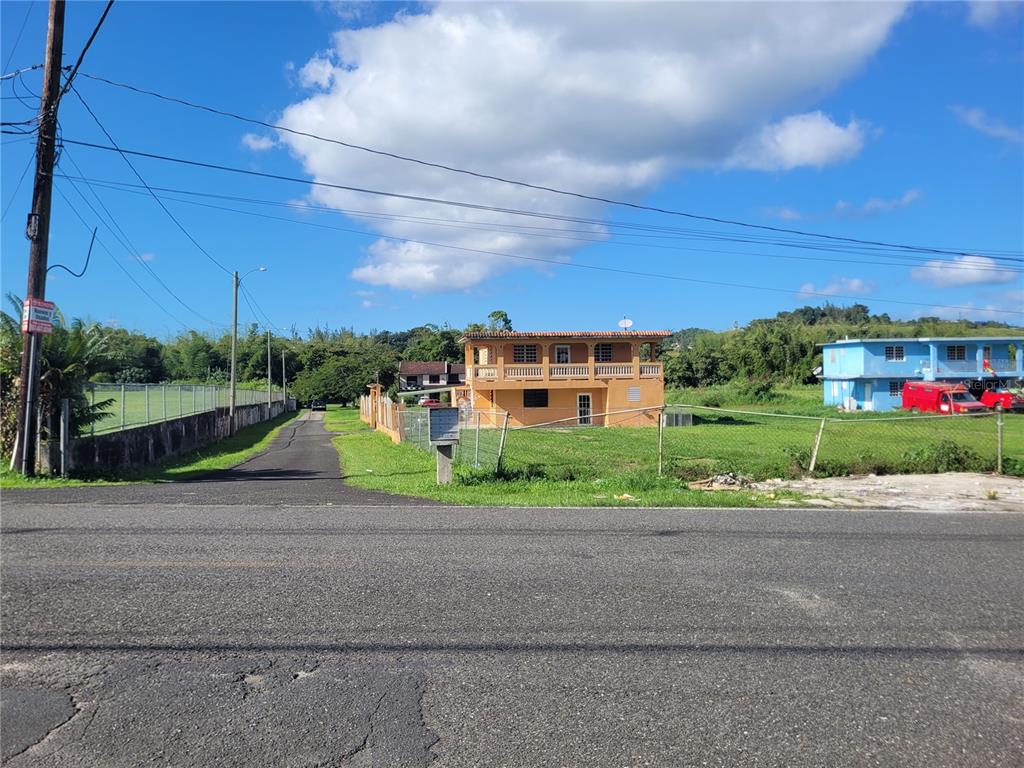 A two-story tan house sits behind a chain-link fence next to a paved driveway — 743 PR 743, CAYEY, PR