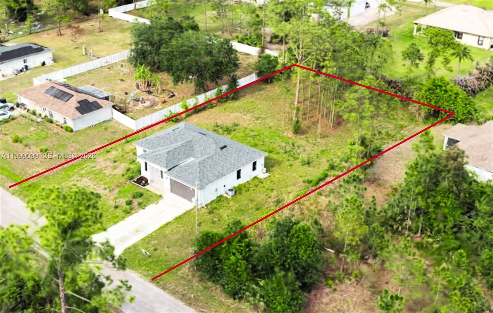 An aerial view shows a single-story house on a large, partially wooded residential lot — 902 MAGNOLIA AVE, Lehigh Acres FL 33972, LEHIGH ACRES, FL