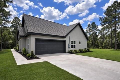 A gray house with a dark roof and a two-car garage sits on a lawn — 13193 BARNEVELDE ROAD, WEEKI WACHEE, FL