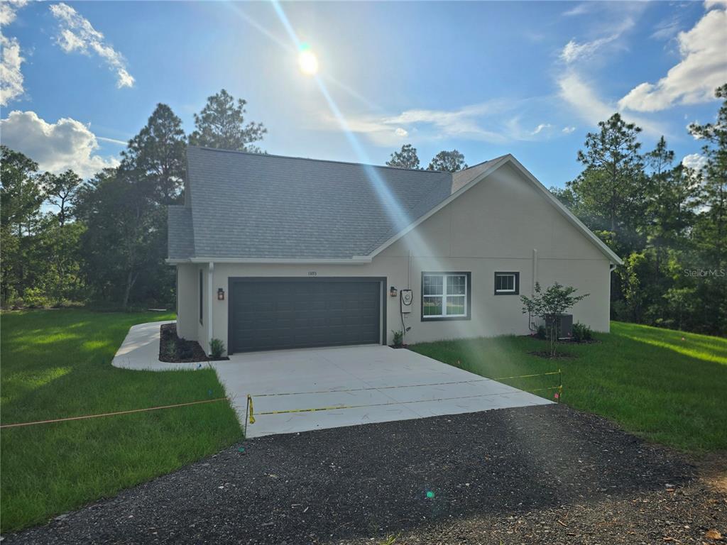 A single-story house with a gray garage door, light-colored stucco siding, and a concrete driveway — 13193 BARNEVELDE ROAD, WEEKI WACHEE, FL