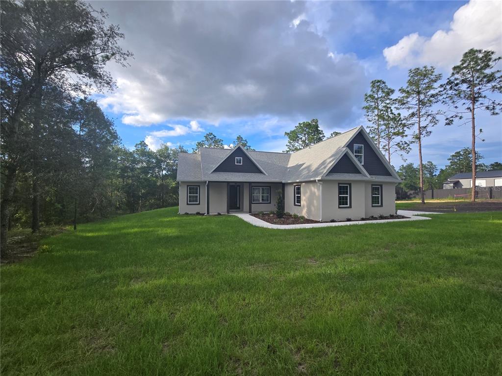 A single-story house with a light-colored exterior, dark gables, and a surrounding grassy lawn — 13193 BARNEVELDE ROAD, WEEKI WACHEE, FL