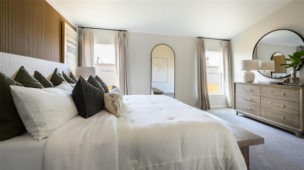 A bedroom features a tufted white bed, wood-slat accent wall, dresser, and arched floor mirror — 33619 NOBLE CREEK PLACE, DADE CITY, FL