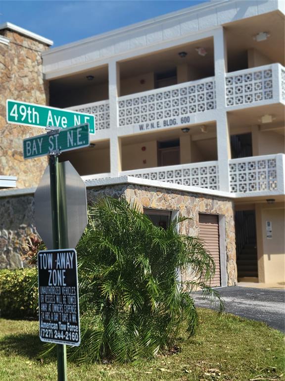 A street sign stands in front of a multi-story building with stone accents and balconies — 4915 BAY STREET NE UNIT 122, ST PETERSBURG, FL