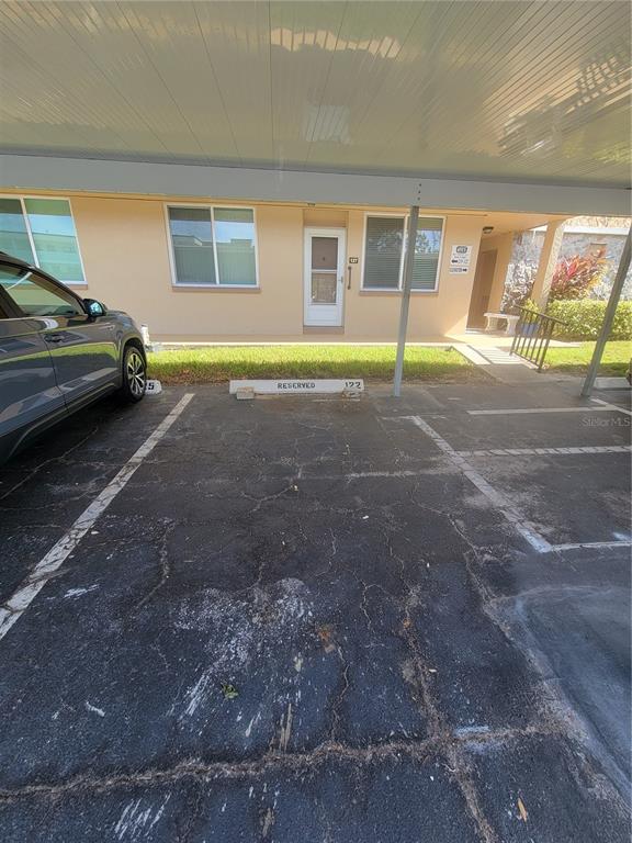 A covered parking space is situated in front of a tan apartment building with windows — 4915 BAY STREET NE UNIT 122, ST PETERSBURG, FL