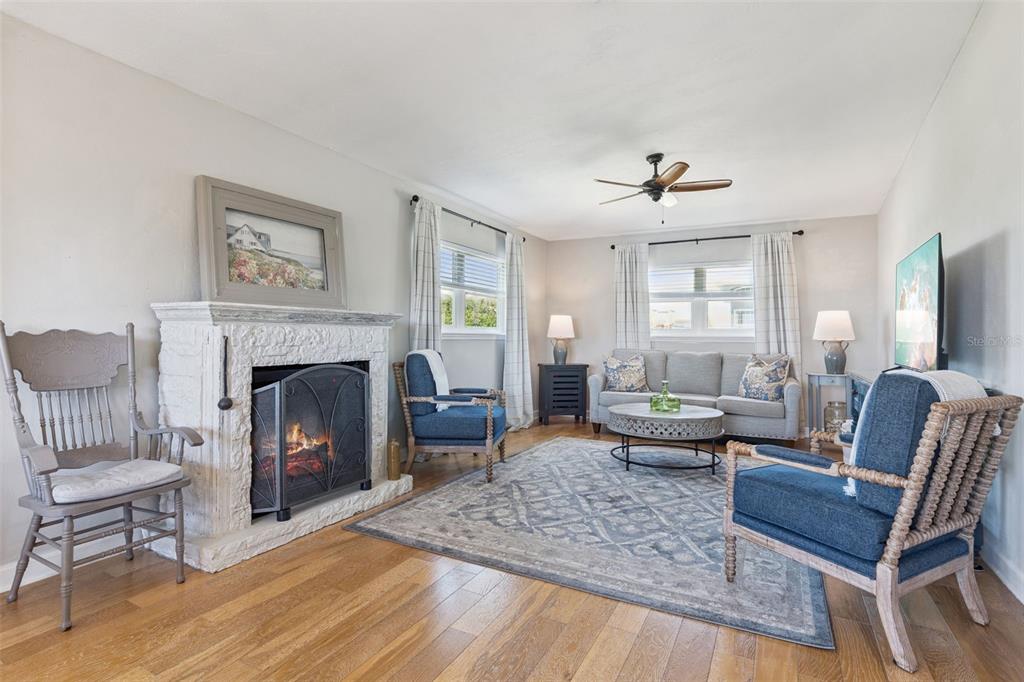 A living room features a stone fireplace, blue armchairs, a gray sofa, and hardwood floors — 884 CATFISH AVENUE, NEW SMYRNA BEACH, FL