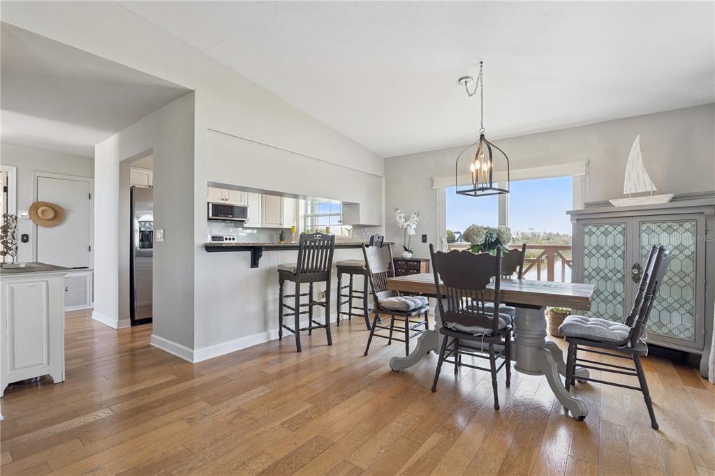 A dining area with a wooden table, chairs, and a breakfast bar overlooking the kitchen — 884 CATFISH AVENUE, NEW SMYRNA BEACH, FL