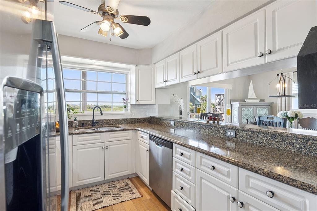 A kitchen features white cabinets, granite countertops, stainless steel appliances, and a window with views — 884 CATFISH AVENUE, NEW SMYRNA BEACH, FL