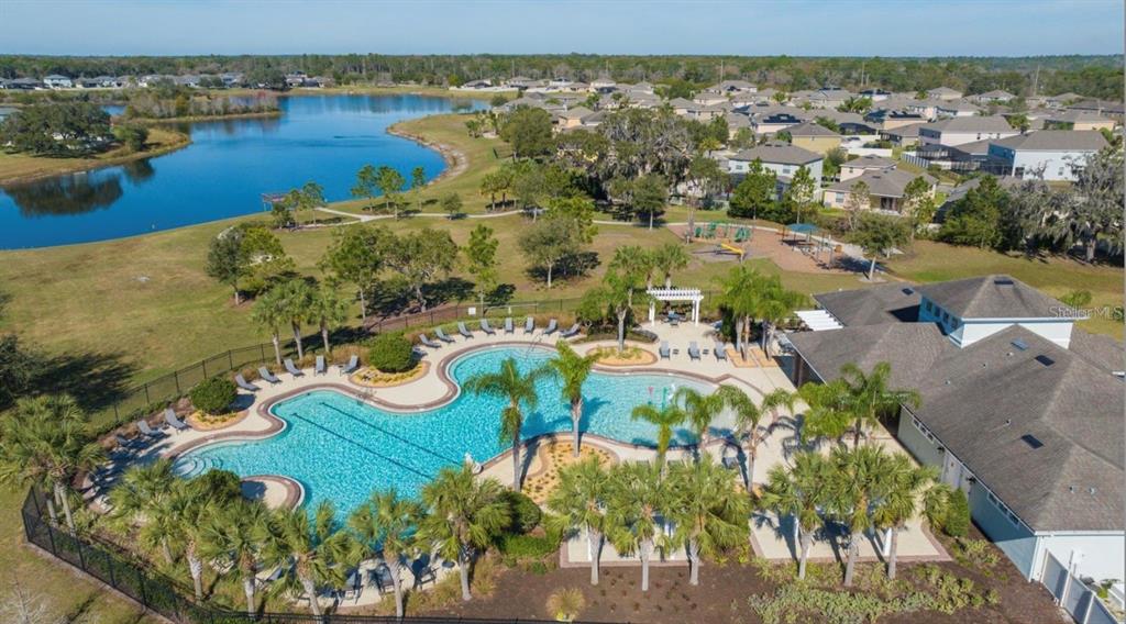 An aerial view shows a community swimming pool, clubhouse, playground, and a nearby lake — 13529 CREST LAKE DRIVE, HUDSON, FL