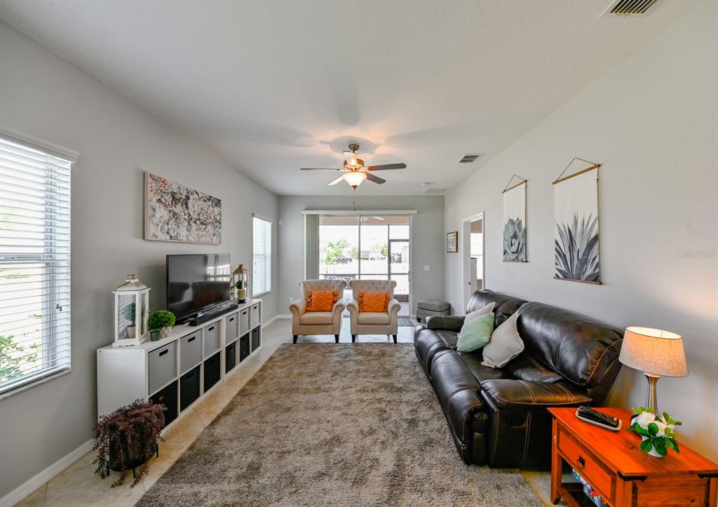 A living room features a dark leather sofa, two armchairs, and a white media console — 13529 CREST LAKE DRIVE, HUDSON, FL