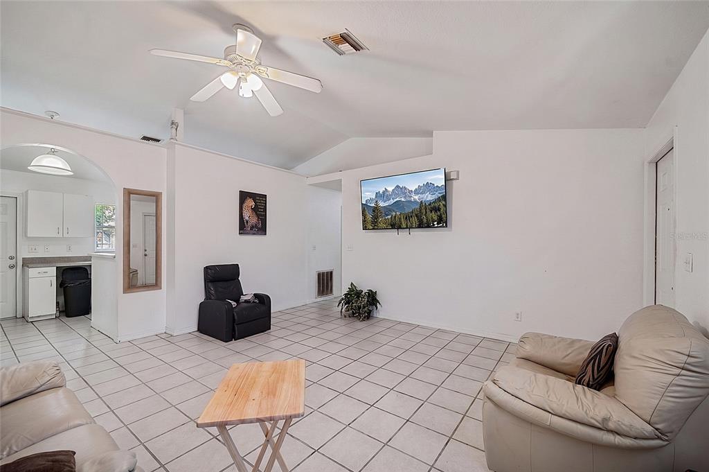 A living room with white walls, tiled floors, a ceiling fan, and a wall-mounted television — 2331 JAYLEN WATKINS STREET, FORT MYERS, FL