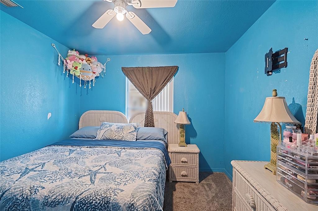 A bedroom features bright blue walls, a white wicker headboard, and a patterned blue bedding set — 2331 JAYLEN WATKINS STREET, FORT MYERS, FL