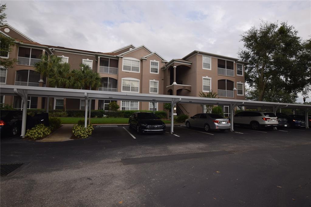 A multi-story apartment building with a covered parking structure in the foreground — 7109 YACHT BASIN AVENUE UNIT 435, ORLANDO, FL